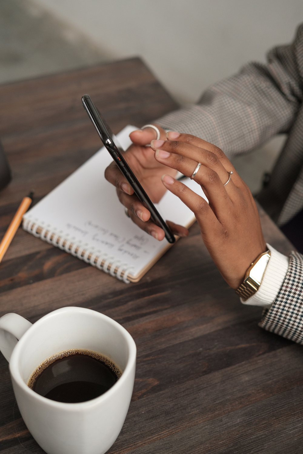 Woman Using Smartphone While Writing Notes